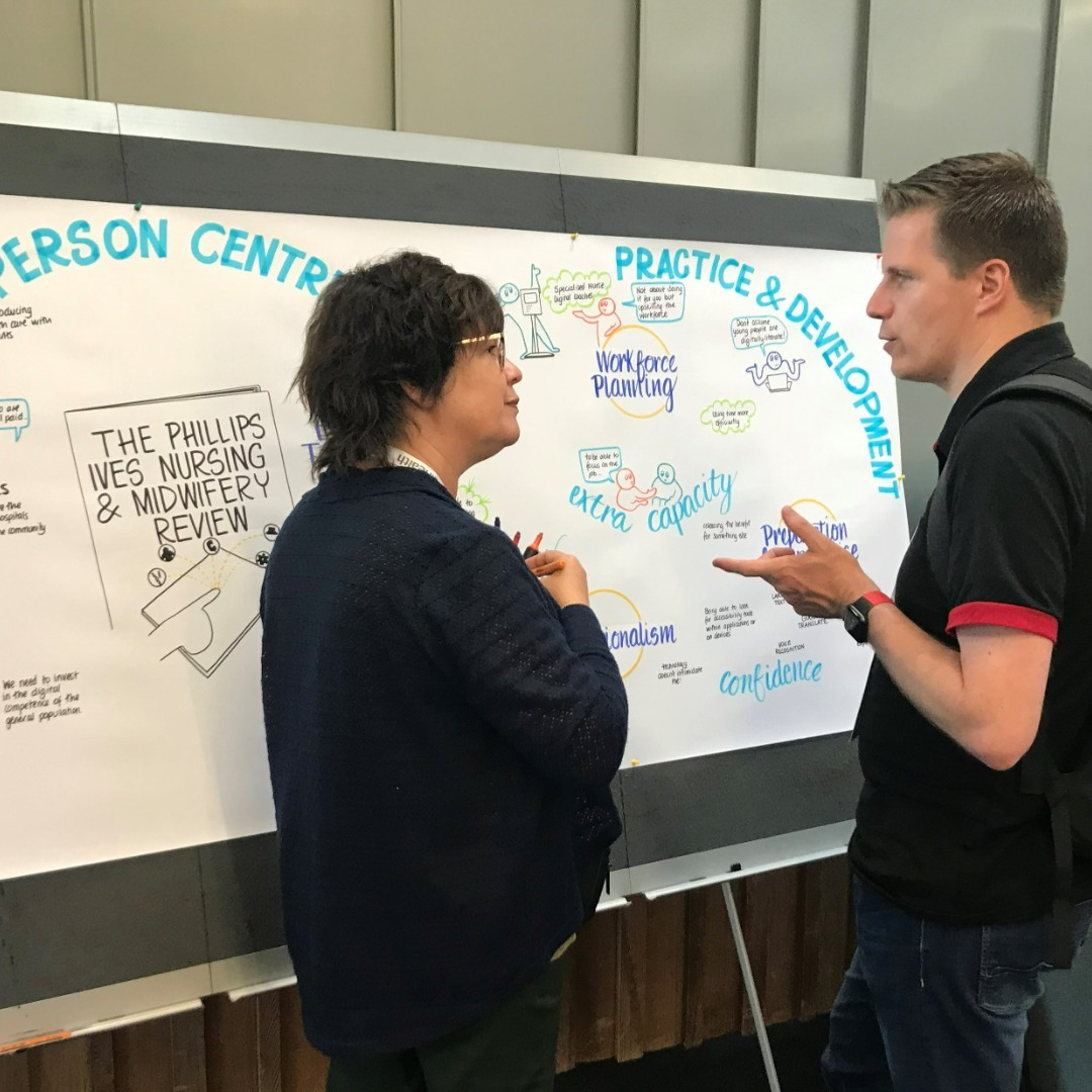 A male and a female in discussion in front of a poster.