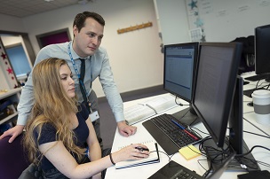Two people at a desk looking at a computer screen