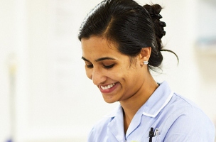 A nurse is smiling while looking down while working on a ward.