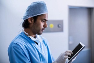 Male surgeon looking at a handheld tablet